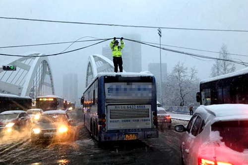 合肥蒙城路桥大雪压电缆挂住公交车 民警爬到车顶托举20多分钟